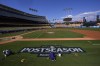 A Los Angeles Dodgers grounds crew member paints the postseason logo on the field prior to practice in preparation for Game 1 of a baseball NL Division Series against the San Diego Padres, Thursday, Oct. 3, 2024, in Los Angeles. (AP Photo/Mark J. Terrill)