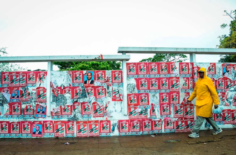A pedestrian passes a wall of election posters in Maputo, Sunday, Oct. 6, 2024, ahead of elections to be held in Mozambique. (AP Photo/Carlos Uqueio)