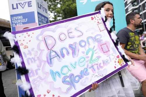 A fan of Taylor Swift holds a sign asking for tickets as she arrives at Wembley Stadium in London for the first of five concerts of Taylor Swift's Eras Tour, Thursday, Aug. 15, 2024. THE CANADIAN PRESS/AP-Alastair Grant