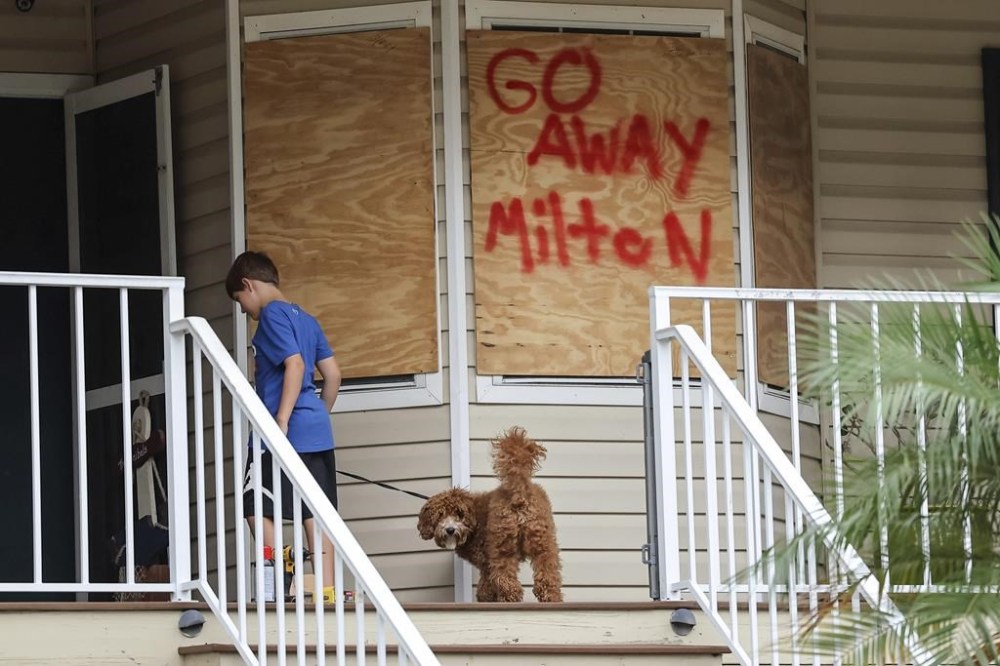 Noah Weibel and his dog Cookie climb the steps to their home as their family prepares for Hurricane Milton on Monday, Oct. 7, 2024, in Port Richey, Fla. (AP Photo/Mike Carlson)