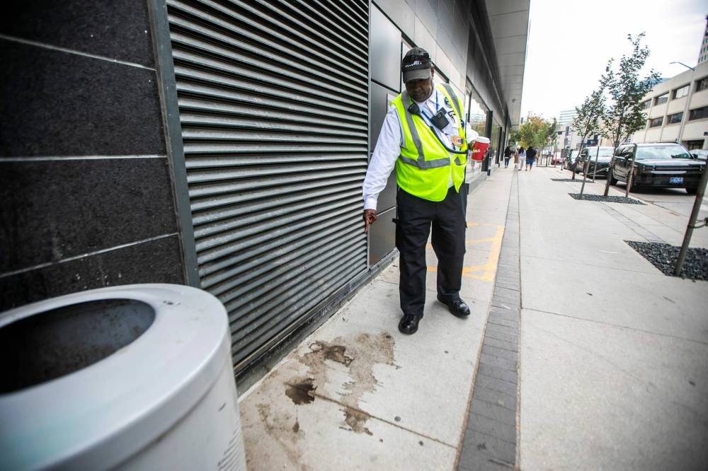 MIKAELA MACKENZIE / WINNIPEG FREE PRESS
                                Abdi Nooh points out urine marks on the sidewalk near the Manitoba Hydro building.