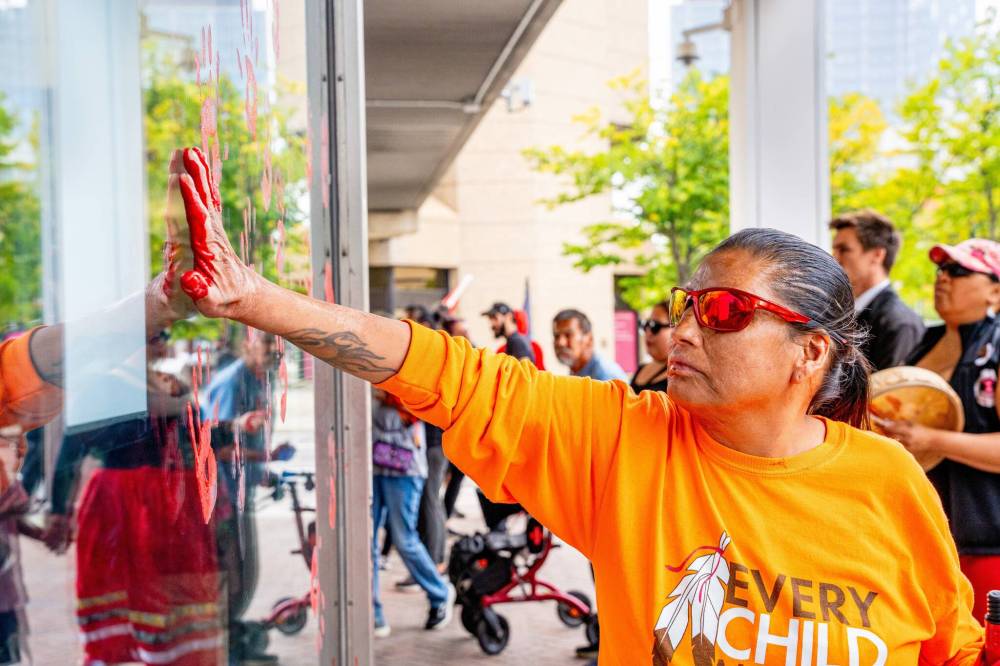 NIC ADAM / FREE PRESS
Irene Bear paints a red handprint on the WPS headquarters after shutting down the intersection at Portage and Main on Sept. 4 after Tammy Bateman, an Indigenous woman, was struck and killed by a police vehicle at a homeless encampment.