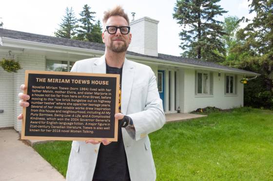 Andrew Unger holds a plaque commemorating novelist Miriam Toews. (Svjetlana Mlinarevic / The Carillon)