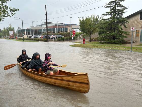 Some people launched kayaks or canoes on flooded residential streets in the Steinbach area after a deluge of rain this week. Pictured from front to back are Hailey Friesen, Wells Penner, and Seth Friesen. (Supplied)