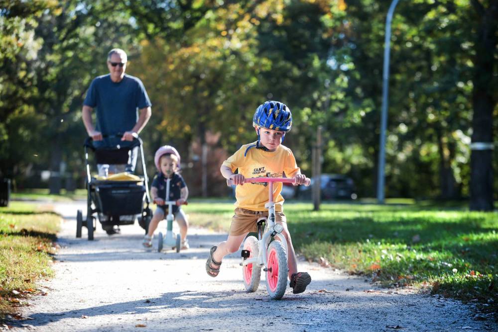 Ruth Bonneville / Free Press
Theo Hildebrand, who turns four next month, races ahead of his two-year-old sister Lucy and his granddad while out for a summer-like jaunt on his slider bike in River Heights Thursday.