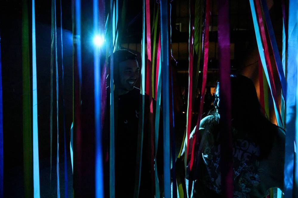 MIKE SUDOMA / FREE PRESS
Festivalgoers Gino (left) and Rina (right) go through the lit-up streamers outside of the Canadian Museum for Human Rights Saturday night as part of Jaimie Issac’s exhibit “Nibi.”