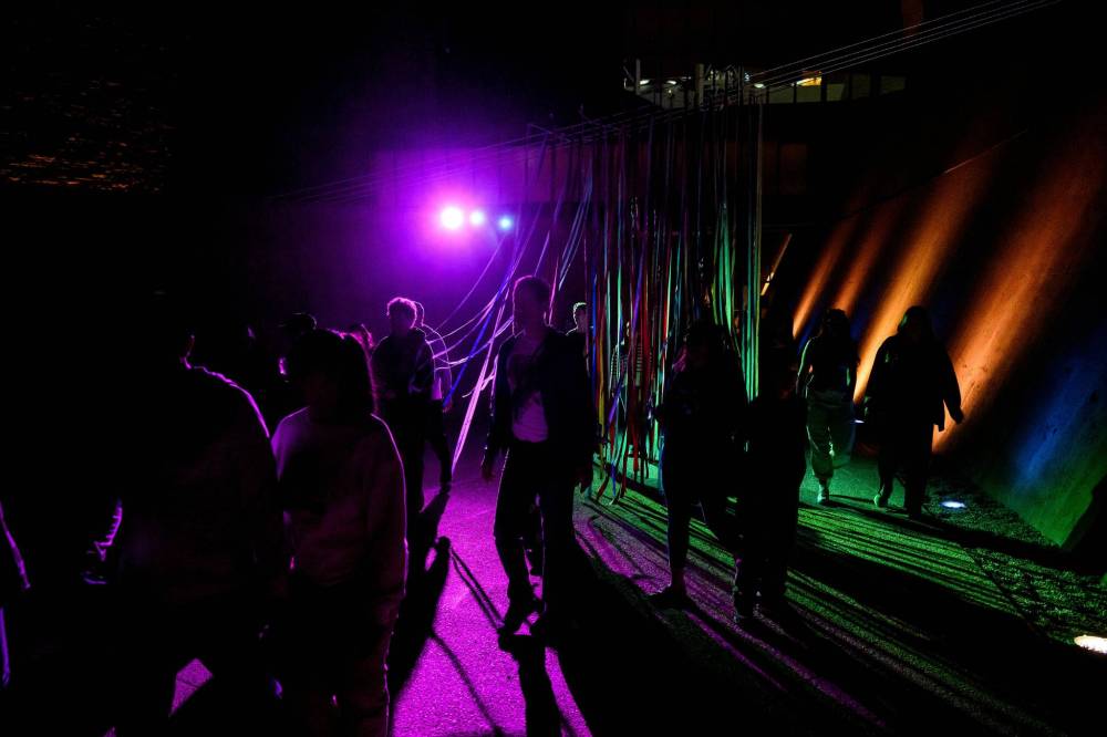 MIKE SUDOMA / FREE PRESS
Nuit Blanche attendees walk through the lit-up streamers outside of the Canadian Museum for Human Rights Saturday night as part of Jaimie Issac’s exhibit “Nibi.”