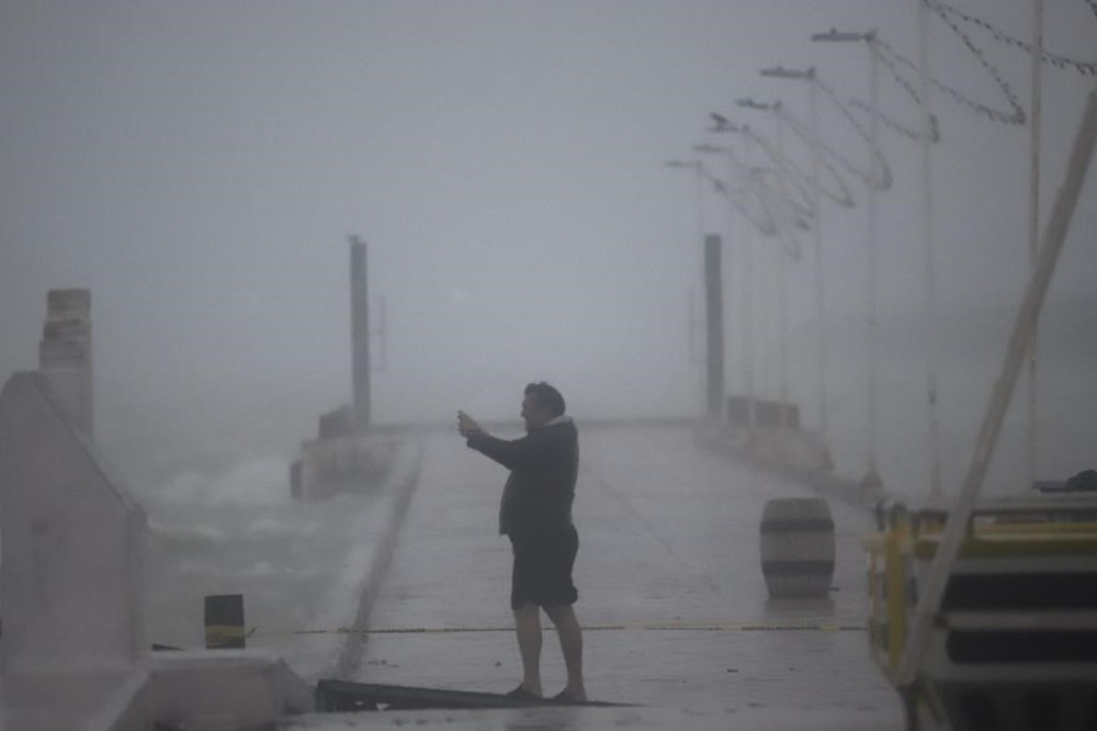 A person takes photos at the harbor amid rain as Hurricane Milton passes near Progreso, Yucatan state, Mexico, Tuesday, Oct. 8, 2024. (AP Photo/Martin Zetina)