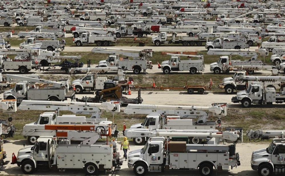 Duke Energy project manager Tiger Yates, bottom center, walks among the hundreds of lineman trucks staged, Tuesday, Oct. 8, 2024. at The Villages, Fla. in preparation for Hurricane Milton. (Stephen M. Dowell/Orlando Sentinel via AP)