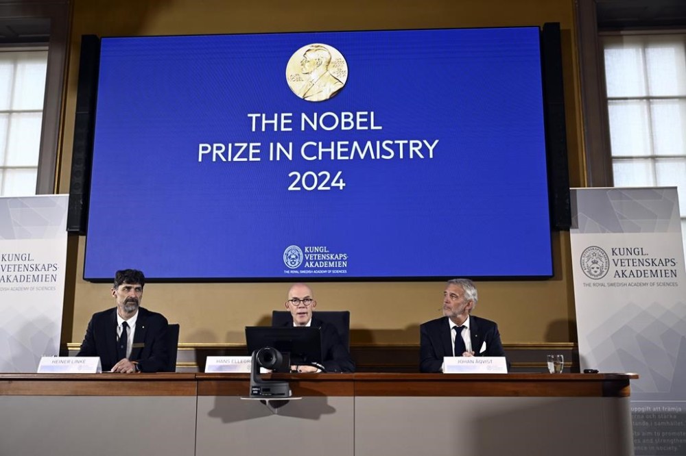 Johan Åqvist, member of the Nobel Committee for Chemistry, Hans Ellegren, Permanent Secretary and Heiner Linke, Chairman of the Nobel Committee for Chemistry award this years Nobel Prize in Chemistry to David Baker, Demis Hassabis, and John Jumper at the Royal Swedish Academy of Sciences, in Stockholm, Sweden, Wednesday, Oct. 9, 2024. (Christine Olsson/TT News Agency via AP)