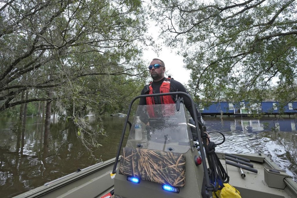 Hillsborough County Master Deputy Robert Unger guides a boat through floodwaters from Hurricane Milton along the Alafia river Friday, Oct. 11, 2024, in Lithia, Fla. (AP Photo/Chris O'Meara)