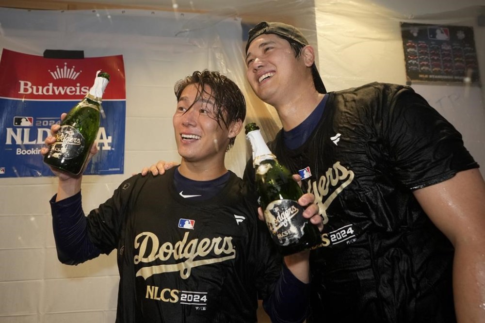 Los Angeles Dodgers' Yoshinobu Yamamoto, left, and Shohei Ohtani celebrate in the clubhouse after a win over the San Diego Padres in Game 5 of a baseball NL Division Series Friday, Oct. 11, 2024, in Los Angeles. (AP Photo/Ashley Landis)