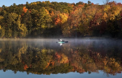An especially warm fall in Ontario means the province may not get the colourful array of fall foliage that usually transforms treetops this time of year. A fisherman in a kayak on Bass Lake is framed by fall colours in central Ontario, Monday, October 10, 2022. THE CANADIAN PRESS/Fred Thornhill