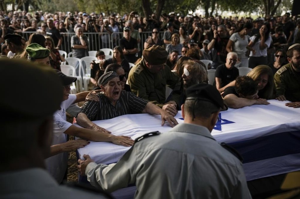 People mourn over the flagged-covered coffin of Israeli soldier Sgt. Amitai Alon, killed by a Hezbollah drone attack, during his funeral near Ramot Naftali, Israel, Monday, Oct. 14, 2024. (AP Photo/Leo Correa)
