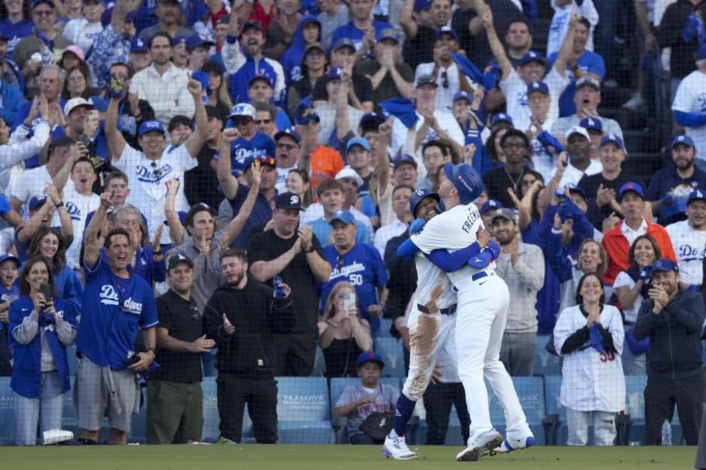 Los Angeles Dodgers' Freddie Freeman, right, and Mookie Betts celebrate after they scored on a single by Max Muncy during the first inning in Game 1 of a baseball NL Championship Series against the New York Mets, Sunday, Oct. 13, 2024, in Los Angeles. (AP Photo/Mark J. Terrill)