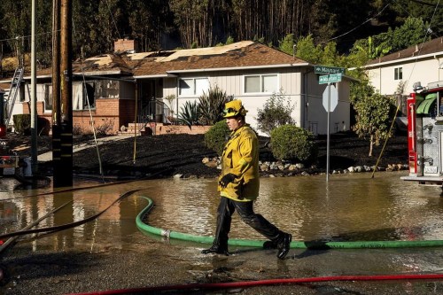 A firefighter passes a home scorched in the Keller Fire near Interstate 580 in Oakland, Calif., Friday, Oct. 18, 2024. (AP Photo/Noah Berger)