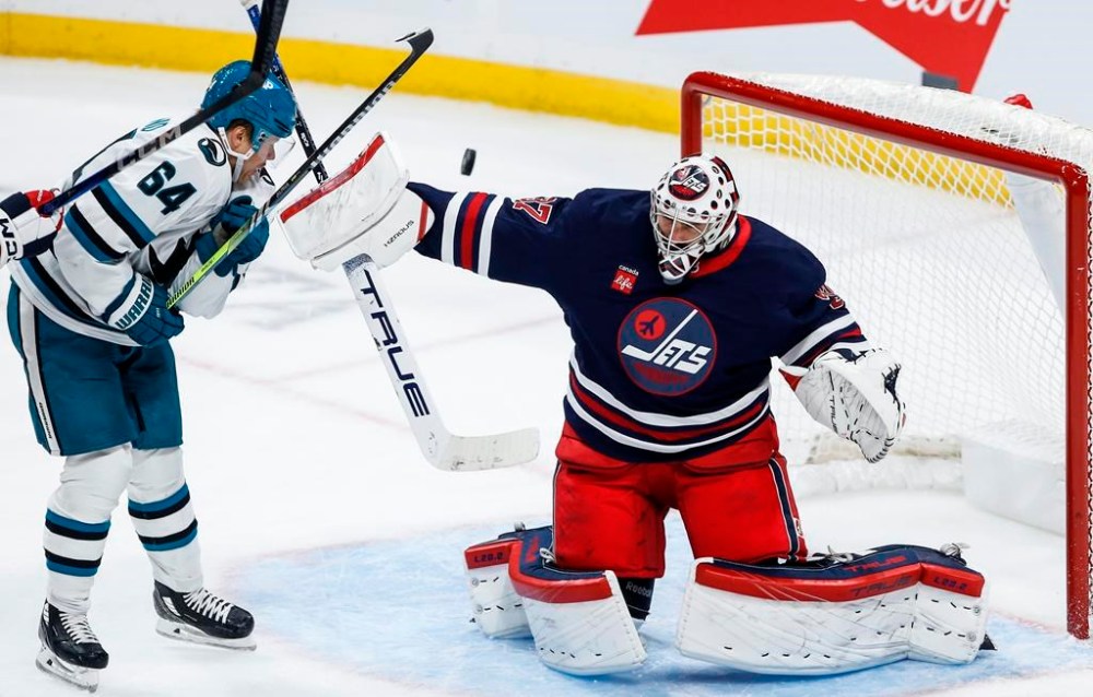 Winnipeg Jets goaltender Connor Hellebuyck (37) saves the tipped shot from San Jose Sharks' Mikael Granlund (64) during third period NHL action in Winnipeg on Friday, October 18, 2024. THE CANADIAN PRESS/John Woods