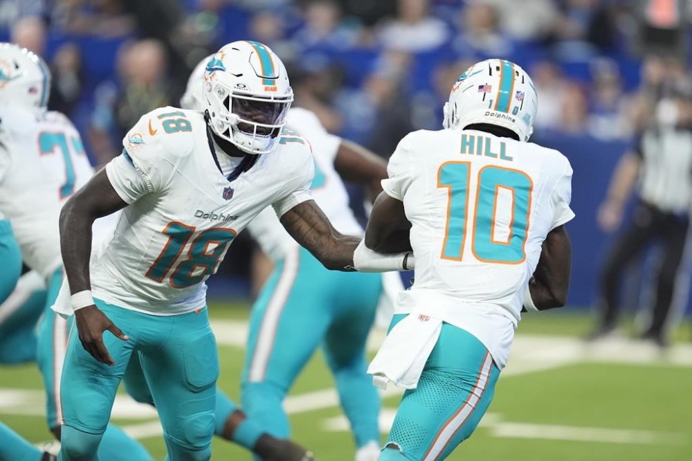 Miami Dolphins quarterback Tyler Huntley (18) hands off to wide receiver Tyreek Hill (10) during the first half of an NFL football game against the Indianapolis Colts, Sunday, Oct. 20, 2024 in Indianapolis. (AP Photo/Michael Conroy)