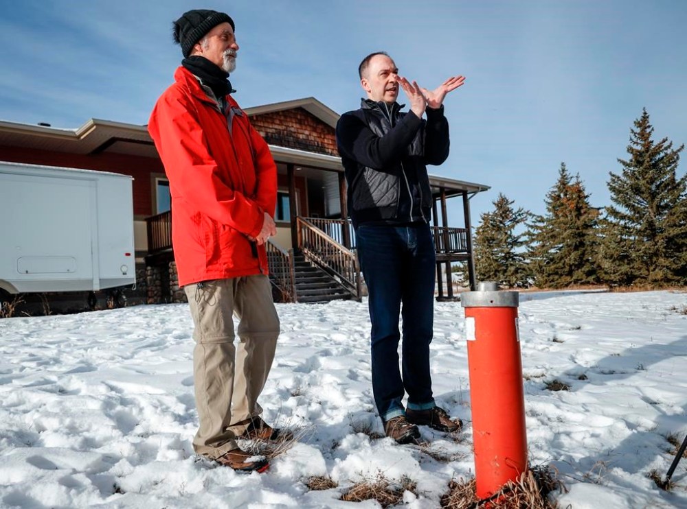 Dr. Aaron Goodarzi, right, scientific director of the Evict Radon National Study, and homeowner Henk de Haan stand beside a water well on de Haan's property near Okotoks, Alta., Thursday, Feb. 22, 2024. THE CANADIAN PRESS/Jeff McIntosh