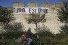 FILE - A man rides a bicycle in front of a banner reading: 