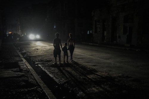 FILE - Residents are illuminated by the headlights of a car during a blackout after a major power plant failed in Havana, Cuba, Oct. 18, 2024. (AP Photo/Ramon Espinosa, File)