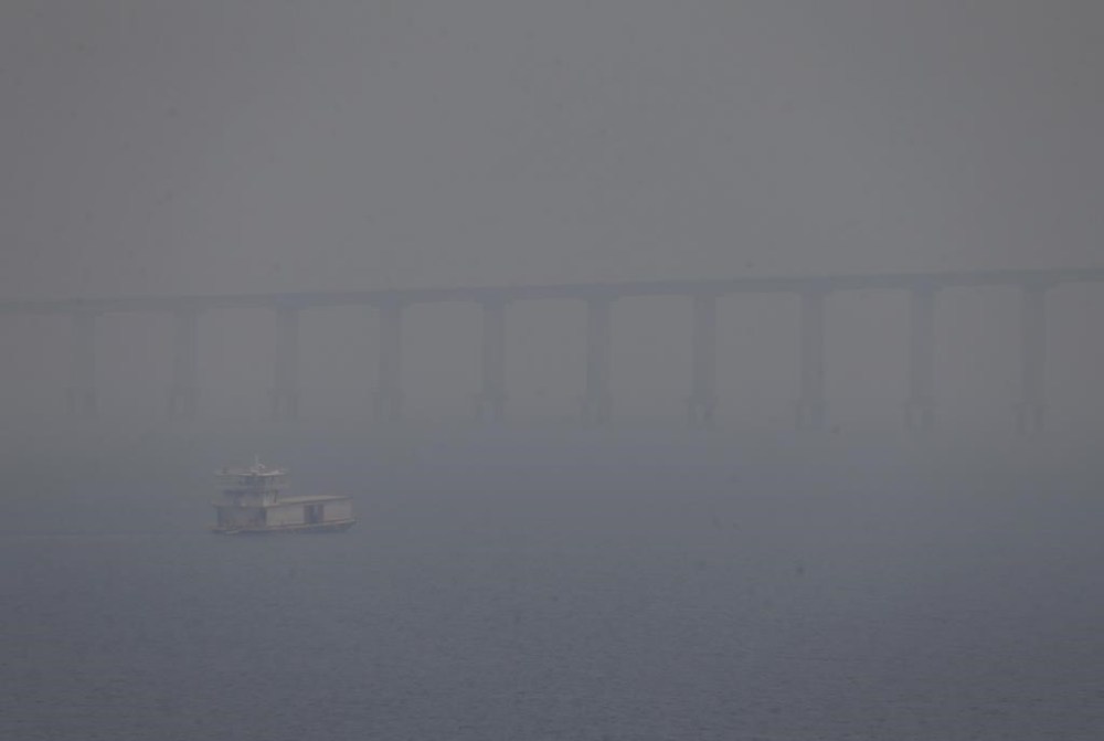 FILE - A boat navigates the Negro River amid smoke from wildfires in Manaus, Amazonas state, Brazil, Aug. 27, 2024. (AP Photo/Edmar Barros, File)