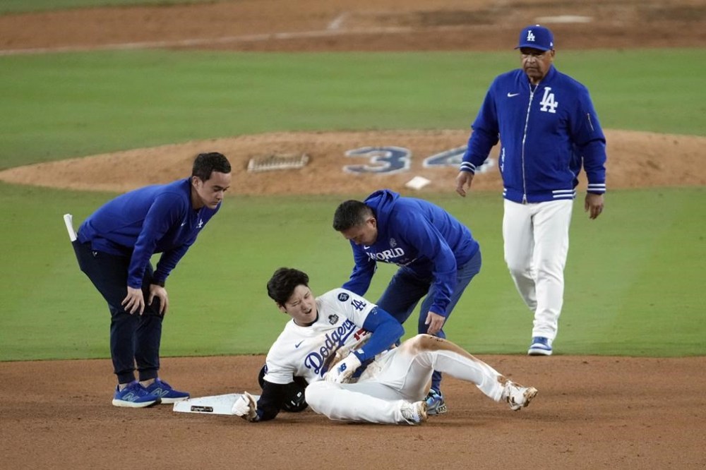 Los Angeles Dodgers' Shohei Ohtani, center, reacts after being injured while trying to steal second base against the New York Yankees during the seventh inning in Game 2 of the baseball World Series, Saturday, Oct. 26, 2024, in Los Angeles. (AP Photo/Julio Cortez)