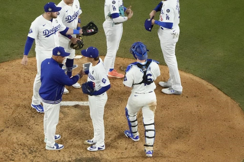 Los Angeles Dodgers pitcher Yoshinobu Yamamoto, center, shakes hands with manager Dave Roberts as he is relieved during the seventh inning in Game 2 of the baseball World Series against the New York Yankees, Saturday, Oct. 26, 2024, in Los Angeles. (AP Photo/Mark J. Terrill)