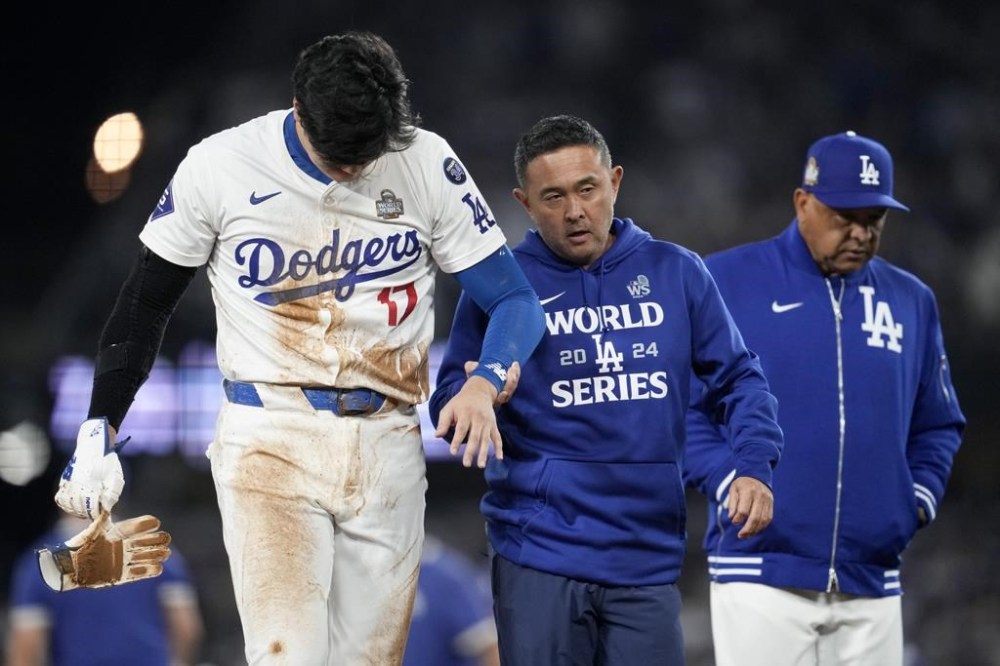 Los Angeles Dodgers' Shohei Ohtani is helped off the field after getting hurt during the seventh inning in Game 2 of the baseball World Series against the New York Yankees, Saturday, Oct. 26, 2024, in Los Angeles. (AP Photo/Ashley Landis)