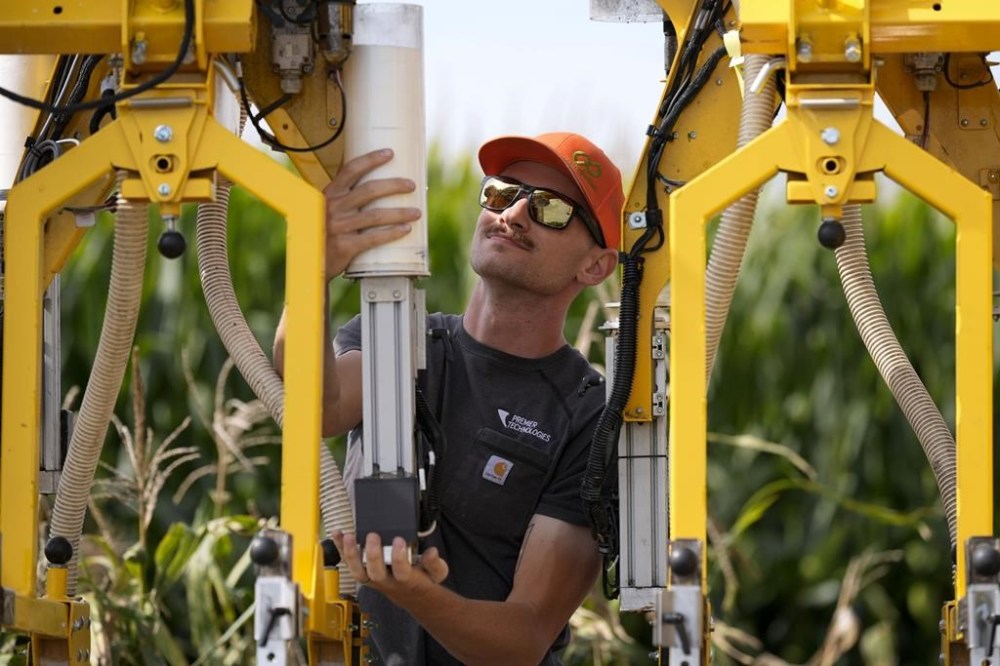 PowerPollen intern Evan Mark prepares a pollen applicator, Thursday, Aug. 22, 2024, near Ames, Iowa. (AP Photo/Charlie Neibergall)