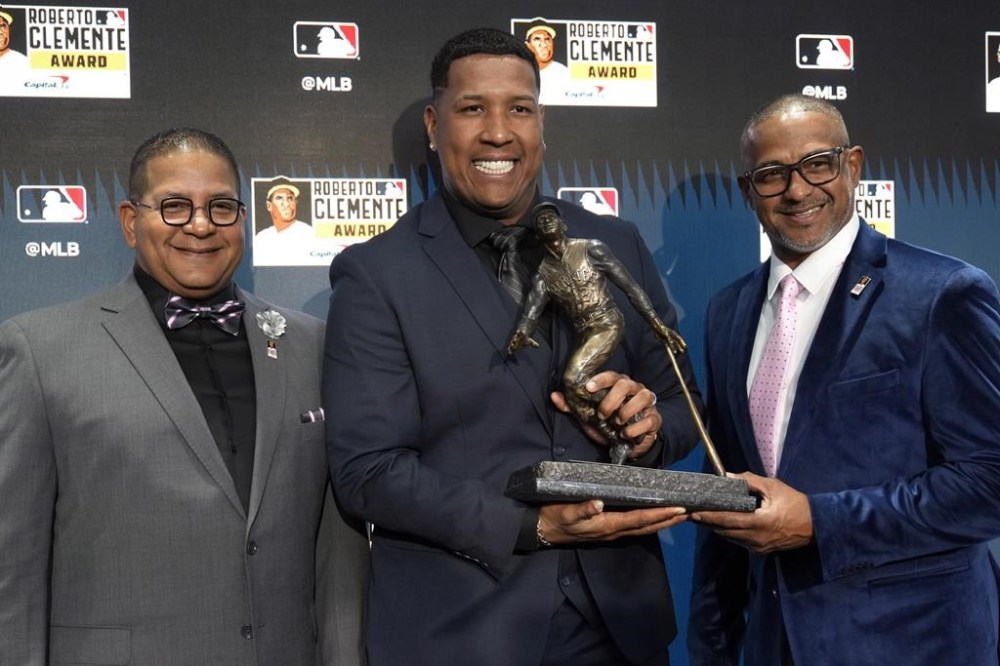 Kansas City Royals' Salvador Perez, center, winner of the 2024 Roberto Clemente Award, poses with Clemente's sons, Luis, left, Roberto Clemente Jr. during a news conference before Game 3 of the baseball World Series between the Los Angeles Dodgers and New York Yankees, Monday, Oct. 28, 2024, in New York. (AP Photo/Seth Wenig)