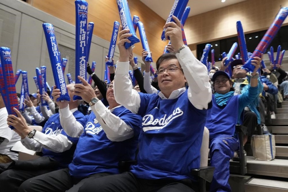 Oshu Mayor Jun Kuranari, center, and other people watch a live stream before the start of Game 3 of the baseball World Series between the Los Angeles Dodgers and the New York Yankees during a public viewing event in Oshu, northeastern Japan, the hometown of Shohei Ohtani of the Los Angeles Dodgers, Tuesday, Oct. 29, 2024. (AP Photo/Eugene Hoshiko)
