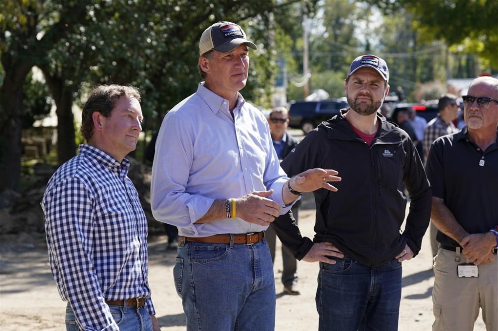 Republican vice presidential nominee Sen. JD Vance, R-Ohio, listens to Virginia Gov. Glenn Youngkin as he visits areas impacted by Hurricane Helene in Damascus, Va., Thursday Oct. 3, 2024. At left is state Sen. Todd Pillion. (AP Photo/Steve Helber)