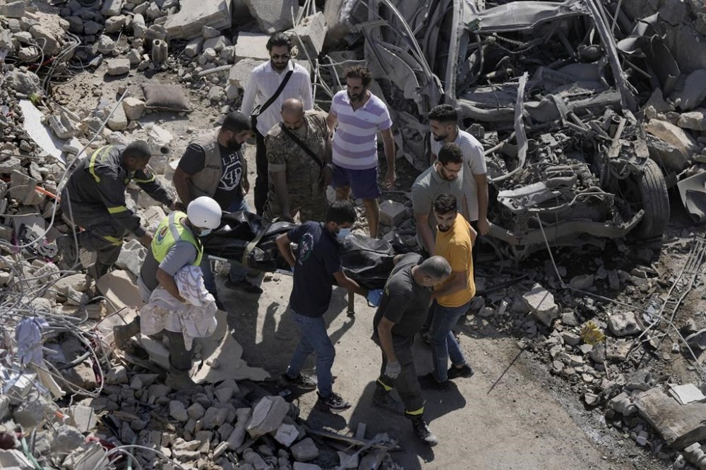 Rescue workers carry the body of a victim retrieved from under the rubble of a destroyed building hit in an Israeli airstrike on Tuesday night, in Sarafand, southern Lebanon, Wednesday, Oct. 30, 2024. (AP Photo/Bilal Hussein)
