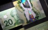 A magnifying glass enlarges the holographic image of Parliament Hill's Peace Tower on a $20 bill issued by the Bank of Canada, shown in a display case at the Bank of Canada Museum in Ottawa, Wednesday, Sept. 4, 2024. THE CANADIAN PRESS/Justin Tang