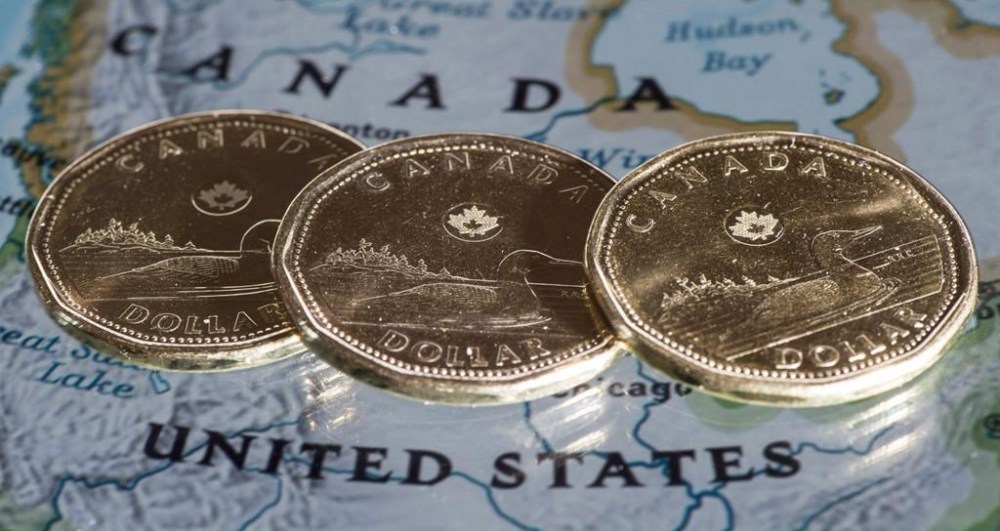 The Canadian dollar is trading against the U.S. dollar at levels not seen since 2020 as the combined pressures of economic outlooks, elections, and energy prices weigh. Canadian dollar coins are displayed on a map along the border of Canada and the United States of America, in Montreal in a January 9, 2014, file photo. THE CANADIAN PRESS/Paul Chiasson