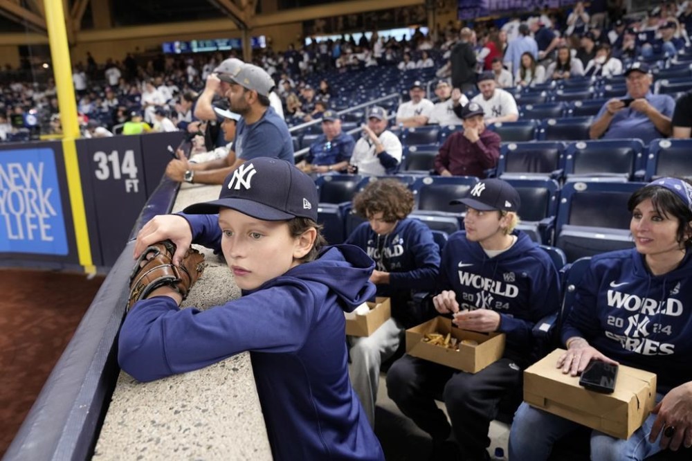 Everett Teel-Young, 11, watches batting practice along with his mother and brothers before Game 5 of the baseball World Series between the Los Angeles Dodgers and New York Yankees, Wednesday, Oct. 30, 2024, in New York. The family was given tickets from the New York Yankees to sit in the seats where fans were ejected during Game 4 after interfering with Los Angeles Dodgers' Mookie Betts as he made a catch.(AP Photo/Seth Wenig)