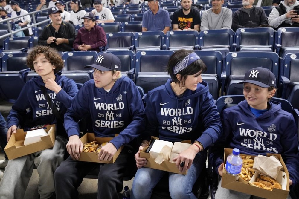 From right to left, Everett Teel-Young sits with his mother, Jacquelyn Teel and brothers Calvin and Trevor, during batting practice before Game 5 of the baseball World Series between the Los Angeles Dodgers and New York Yankees, Wednesday, Oct. 30, 2024, in New York. The family was given tickets from the New York Yankees to sit in the seats where fans were ejected during Game 4 after interfering with Los Angeles Dodgers' Mookie Betts as he made a catch.(AP Photo/Seth Wenig)
