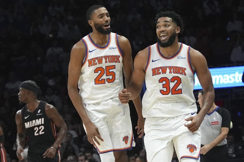 New York Knicks center Karl-Anthony Towns (32) celebrates after scoring during the second half of an NBA basketball game against the Miami Heat, Wednesday, Oct. 30, 2024, in Miami. At left is New York Knicks forward Mikal Bridges (25). (AP Photo/Lynne Sladky)