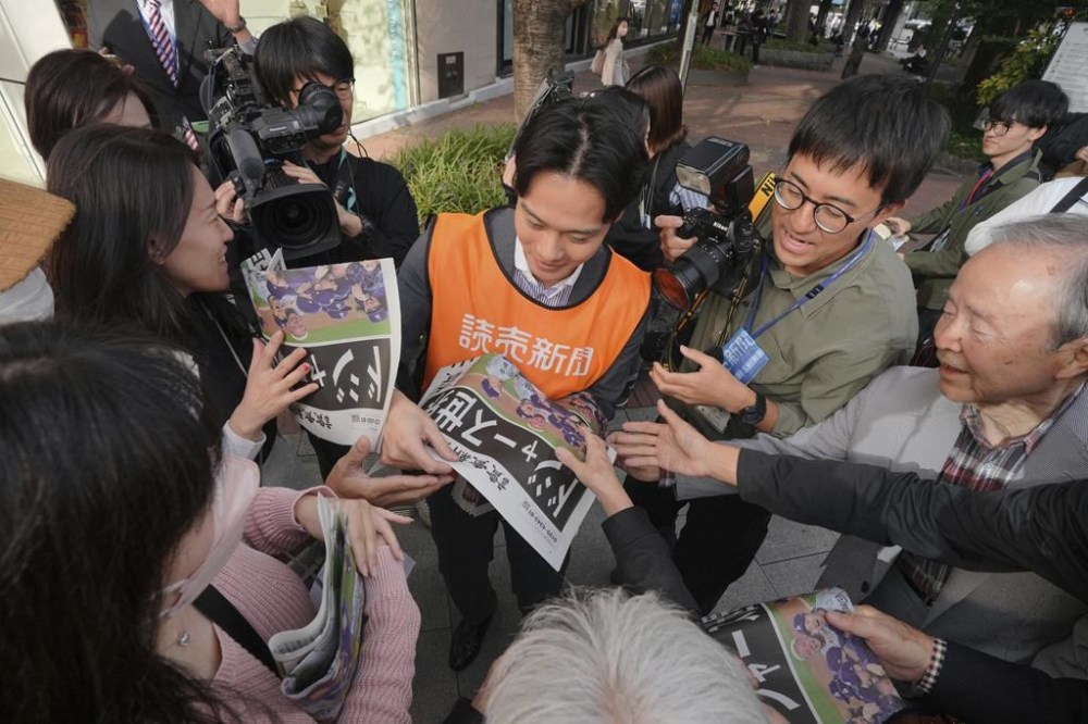 A staff member distributes an extra edition of the Yomiuri Shimbun newspaper in Tokyo, Thursday, Oct. 31, 2024, reporting on the Los Angeles Dodgers' victory in the World Series baseball match after the Dodgers defeated the New York Yankees in Game 5 in New York. The headline of the newspaper said