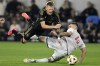 Los Angeles FC midfielder Mateusz Bogusz, left, gets tripped by Vancouver Whitecaps defender Ranko Veselinovic (4) during the second half of the first match of an MLS Cup playoffs opening round in Los Angeles, Sunday, Oct. 27, 2024. Heading into a do-or-die playoff matchup against Los Angeles FC on Sunday, the 'Caps know they need to be at their best. (AP Photo/Alex Gallardo)