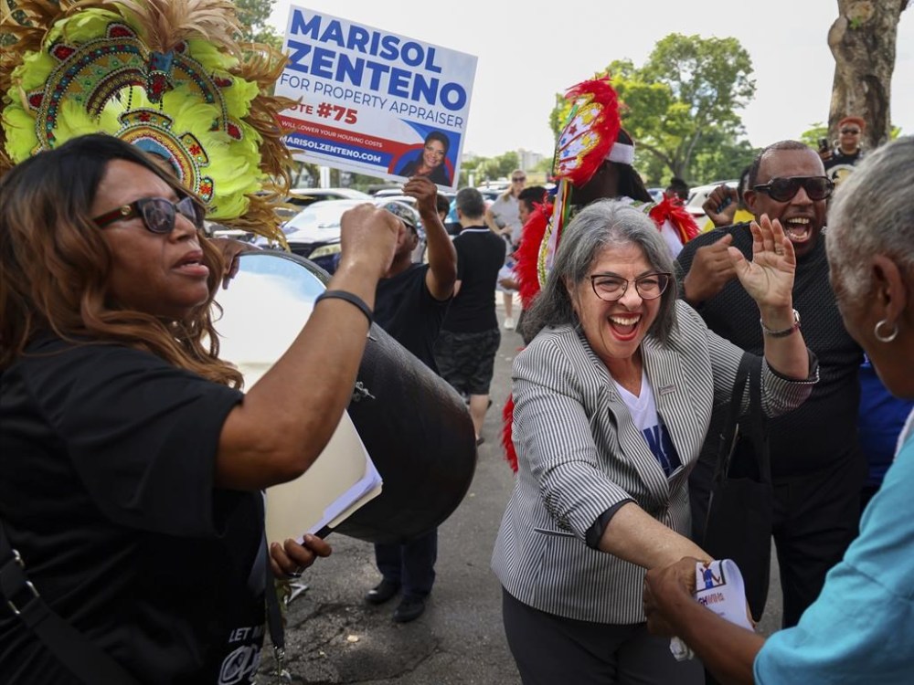 Democratic candidates, Mayor Daniella Levine Cava, right, and unincorporated Miami-Dade voters dance to the sounds of the Bahamian Junkanoo band during a festive visit to the polls at the Joseph Caleb Center during the