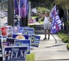 A campaign volunteer carries a Harris-Walz flag while waving to voters in line during early voting at the Orange County Supervisor of Elections precinct on Kaley Avenue in Orlando, Fla., Friday, Oct. 25, 2024. (Joe Burbank/Orlando Sentinel via AP)