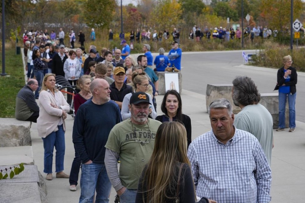 Voters line up to vote as a early voting location opened in Carmel, Ind., Wednesday, Oct. 23, 2024. (AP Photo/Michael Conroy)