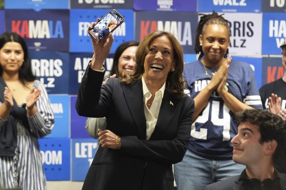 Democratic presidential nominee Vice President Kamala Harris holds up a phone as she phone banks with volunteers at the DNC headquarters on Election Day, Tuesday, Nov. 5, 2024, in Washington. (AP Photo/Jacquelyn Martin)