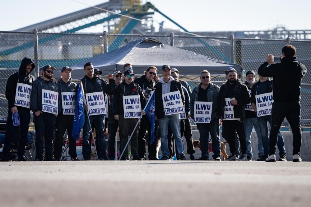 Workers pose for a photo while picketing at Neptune Terminal during an International Longshore and Warehouse Union labour dispute in North Vancouver, on Tuesday. Canadian retailers say their frustration is growing with what they describe as a lack of urgency to resolve disruptions at Canada's two largest ports. THE CANADIAN PRESS/Ethan Cairns
