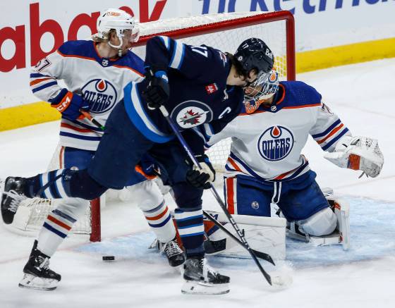 Jets captain Adam Lowry crowds the front of the Edmonton Oilers net and goaltender Stuart Skinner during action between the teams last season. (John Woods / The Canadian Press files)