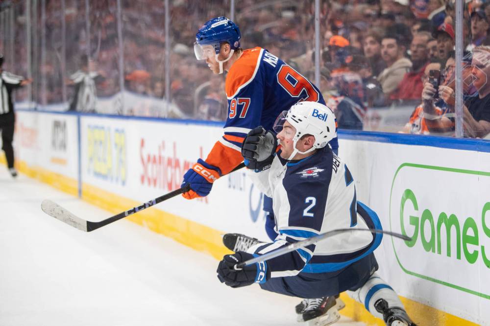 Amber Bracken / THE CANADIAN PRESS
Winnipeg Jets defenceman Dylan DeMelo is checked hard by Edmonton Oilers’ captain Connor McDavid during the second.