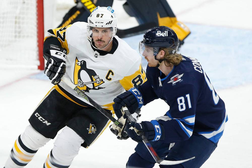 JOHN WOODS / FREE PRESS FILES
Pittsburgh’s Sidney Crosby (left) tries to elude the check from Jets forwarsd Kyle Connor during a game in Winnipeg on Nov. 22, 2021.