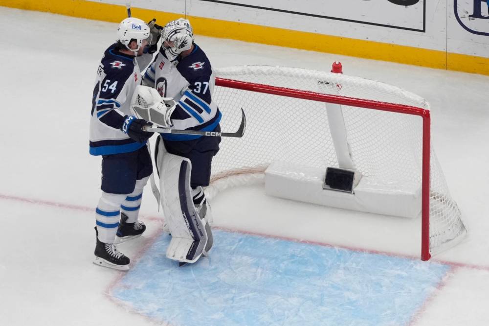 Winnipeg Jets goaltender Connor Hellebuyck and Dylan Samberg (left) celebrate a 3-2 victory over the St. Louis Blues Tuesday in St. Louis. (Jeff Roberson / The Associated Press)